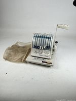 Paymaster Ribbon Writer machine with cover displayed beside