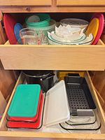 Drawer showing nesting glass bowls, Pyrex measuring cup, plastic containers and lids