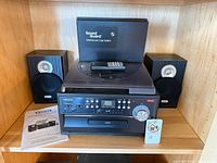 Full view of stereo unit with dust cover, remote, two speakers and manual