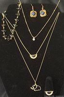 All six jewelry pieces displayed on bust: three necklaces, earrings, bracelet, ring