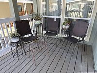 Overall lot showing four brown patio chairs, three plant stands, and potted plants on deck