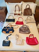 Overview of all eleven handbags laid out on bed