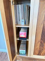 Cabinet view showing vinyl LPs on upper shelf, two trays of CDs on middle and lower shelves