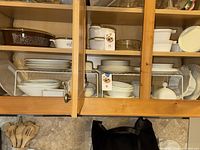 Cabinet view showing multiple shelves of ivory dinnerware pieces
