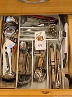 Drawer view of Oneida flatware stacks and assorted utensils