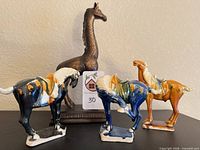 Group view of giraffe and three glazed horses