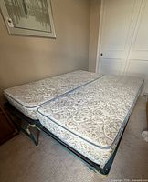 Two twin mattresses laid side by side on teal metal frames