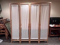 Front view of folded four-panel room divider showing wood frame and white fabric inserts