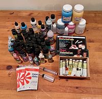 Overall lot on table showing majority of paints, dyes, Pentel sets, wooden tube box, applicators