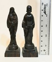 Full view of both ebony figurines beside ruler showing height
