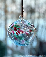 Hanging clear glass sphere ornament showing interior multicolor swirls and glass loop