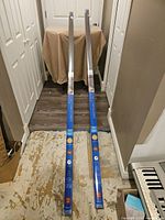 Two sealed Coolaroo roller shade packages laid on floor, full length view