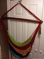 Full view of hammock chair hanging, showing wood bar, ropes and seat