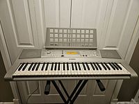 Front view of Yamaha keyboard on stand with music rest attached