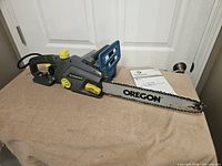 Left side view of Yardworks electric chainsaw with Oregon bar and instruction manual