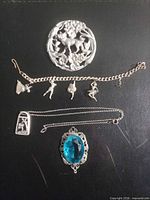Full lot overview showing brooch, bracelet, blue pendant, and necklace with arched pendant