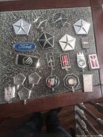 Full lot overview showing all chrome hood and grille ornaments on tabletop