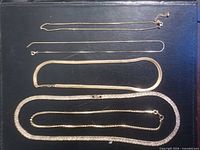 Five gold-tone necklaces laid out showing length and style