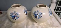 Pair of cream ceramic vases front view showing floral motif