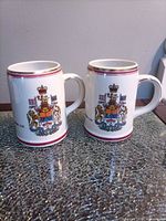 Front view showing Canadian coat of arms on both mugs