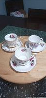 Three teacup and saucer pairs displayed on wooden board