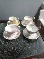 All four teacup and saucer sets on glass surface