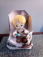 Front view of boxed Luke Skywalker plush with lightsaber