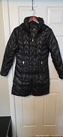 Front view of black quilted puffer jacket hanging