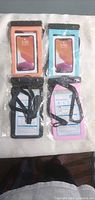 Front view of all four packaged waterproof phone pouches in orange, blue, black, pink