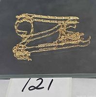 Full view of tangled broken gold chain on dark surface