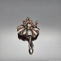 Front view of bronze ballerina brooch on neutral background