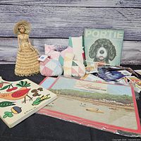 Group shot showing all items: straw doll, pillows, Portie sign, booklet, puzzle, bag of packs