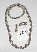 Necklace, bracelet, earrings set laid flat showing overall design