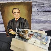 Both paintings together: portrait upright, nautical piece partially rolled