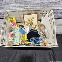 Box overview showing dolls, Thumb Saver box, booklet, framed print and other ephemera
