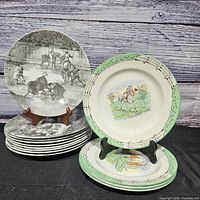 Stack of plates showing both pattern types, front plate on stand displays green border fox-hunt design