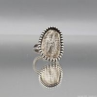 Front view showing oval textured face with beaded border