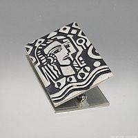 Front view showing abstract face design on silver-tone brooch