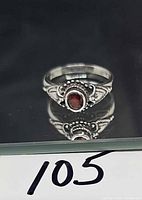Front view of sterling silver ring showing red stone and filigree design
