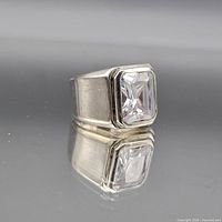 Ring front showing emerald-cut stone and bezel setting