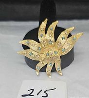 Front view showing goldtone starburst design with turquoise cabochons and clear rhinestones