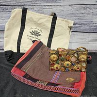 Canvas tote with printed orchestra logo, beaded clutch displayed in front