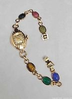 Front view of Bulova watch attached to multicolor scarab link bracelet