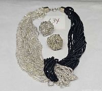 front view showing entire necklace half clear, half black, woven knot and both earrings