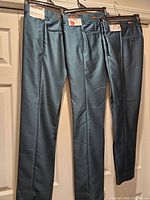 Three pairs of Egara dress pants hanging on hangers