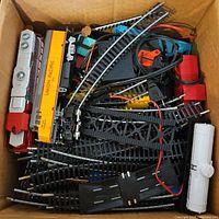 Overview of box showing mixed HO track, bridge parts, Union Pacific car, diesel loco, white tank car