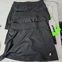 Four stacked Prince girls tennis skorts with tags visible