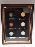 Full view of framed shadow box with six golf balls and plaques
