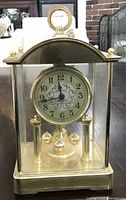 Front view of brass and glass Brentwood mantel clock showing dial, case, and rotating pendulum