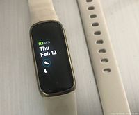 Front view of Fitbit Luxe powered on with white strap segments